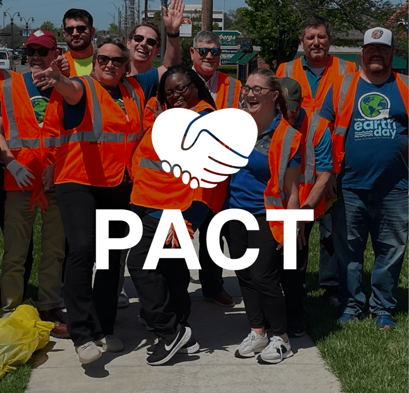 People in orange construction vest with the pact logo over it